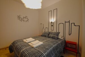 Dormitorio con cama doble decorado con cojines y toallas y 2 mesitas de noche.